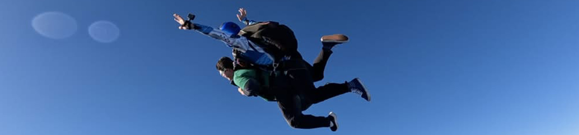 An NFB of Oregon member spreads their arms wide while tandem sky diving.