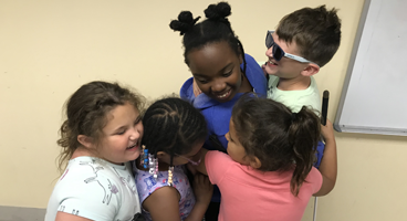 Five NFB BELL students smile in a group hug.